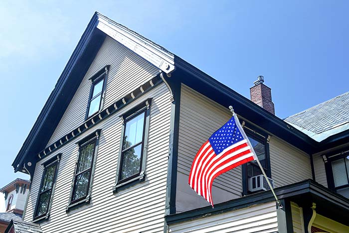 An American Flag flying in front of an old Colonial style house.